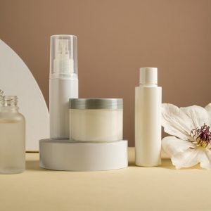 Blank cosmetics jars and bottles with white flower. Beauty concept, neutral background