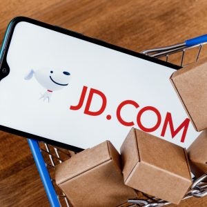 JD.com is a Chinese e-commerce company. Smartphone with JD.com logo on the screen and parcels in shopping cart.